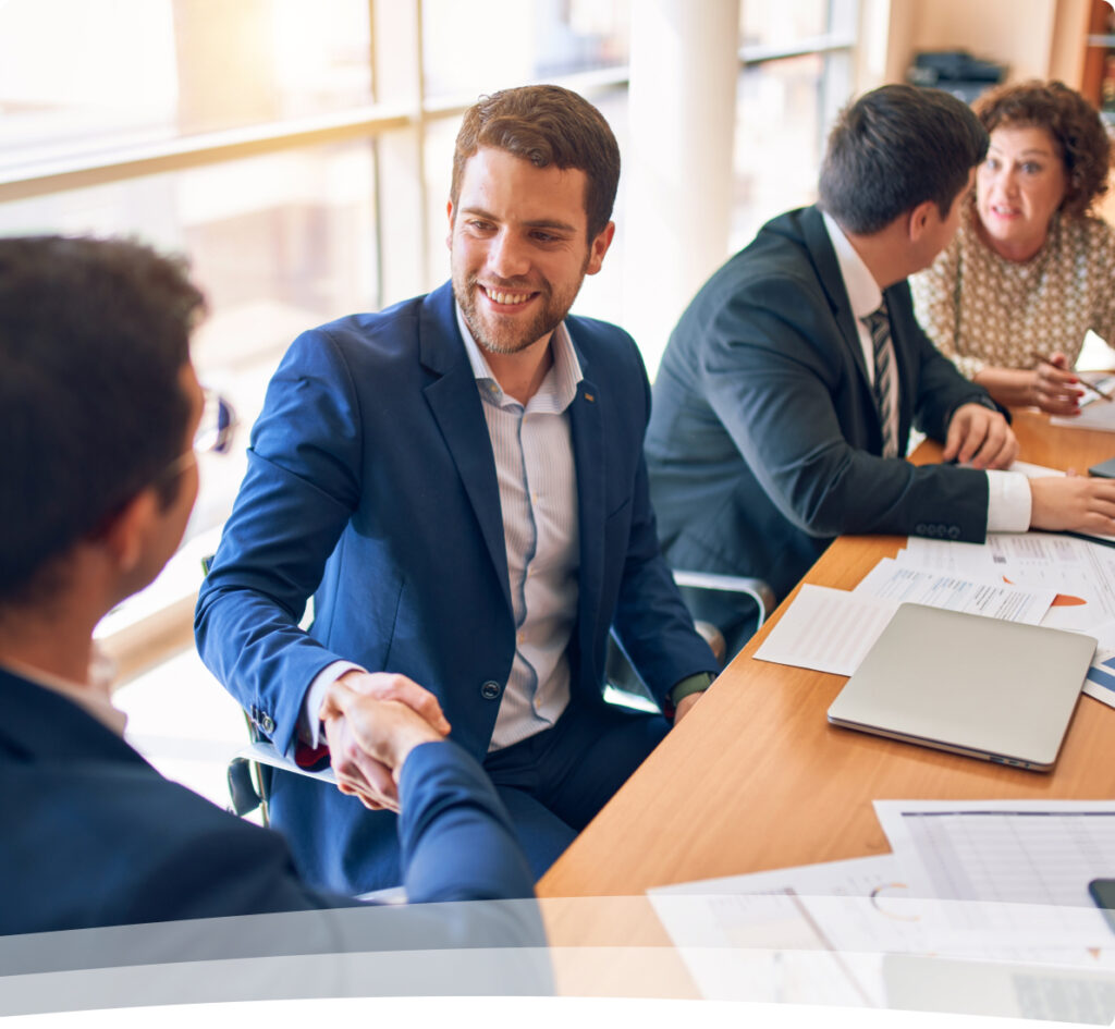 a man shaking hands with another man sitting at a table